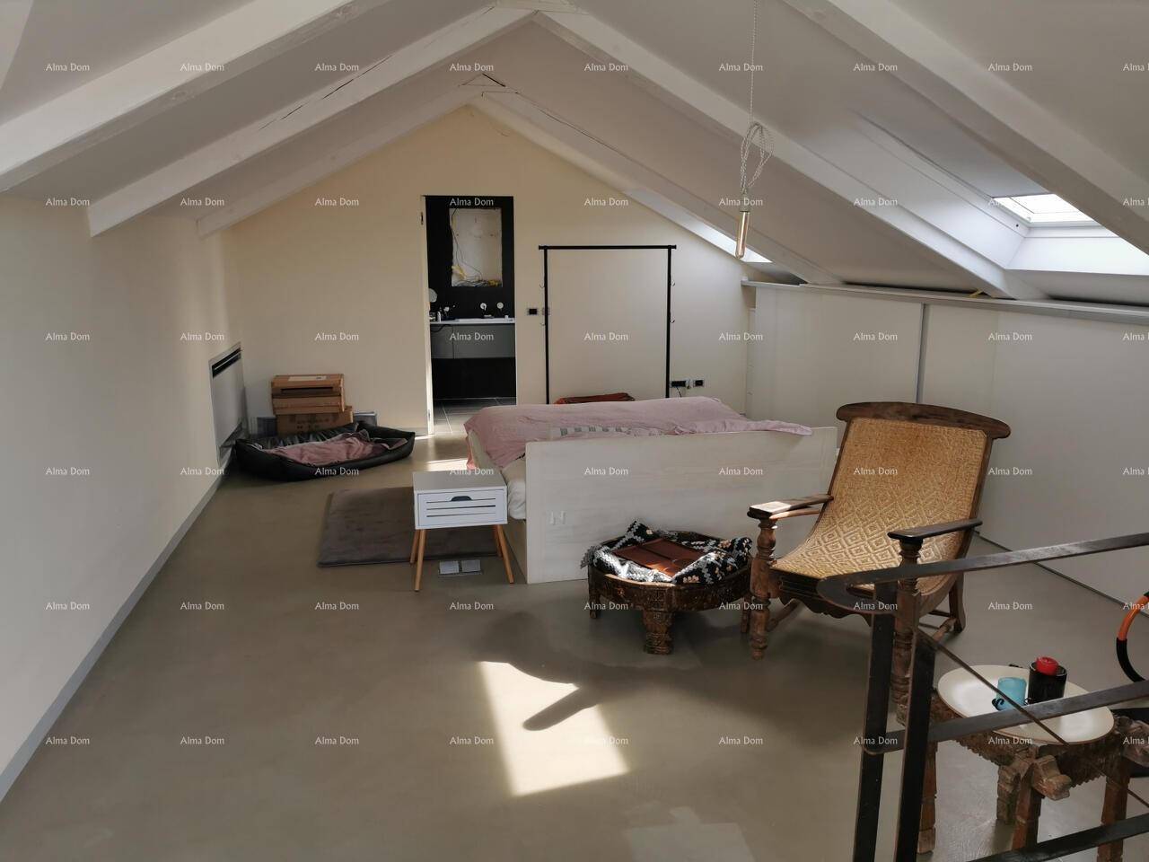 Geräumiges Dachgeschoss-Schlafzimmer mit sichtbaren Holzbalken, Dachfenstern und modernem Ambiente.