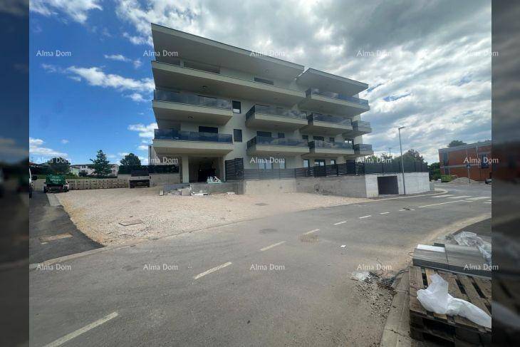 Modernes Apartmentgebäude mit Balkonen und Flachdach, umgeben von Baustellenmaterialien.