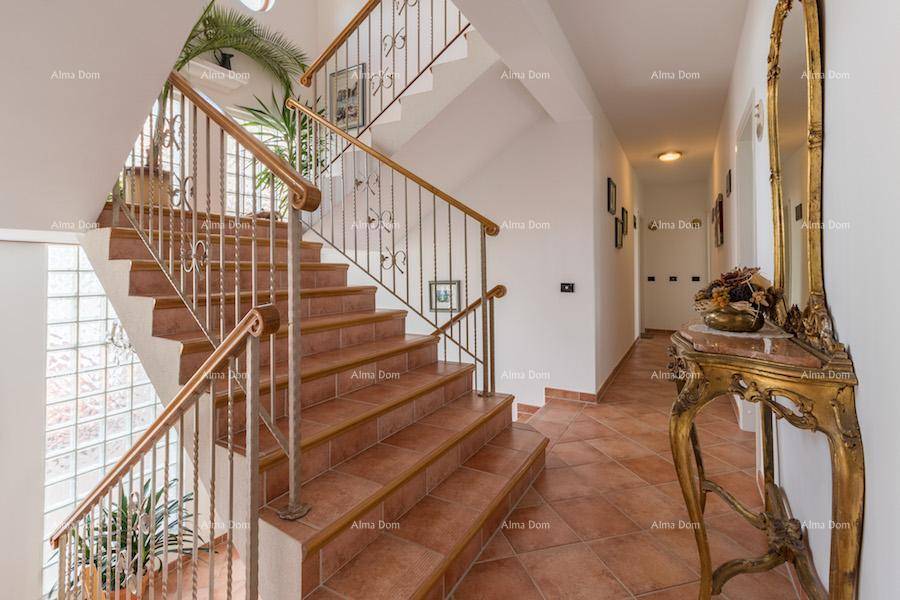 Elegante Treppe mit schmiedeeisernem Geländer und Holzhandlauf, die die Etagen verbindet.