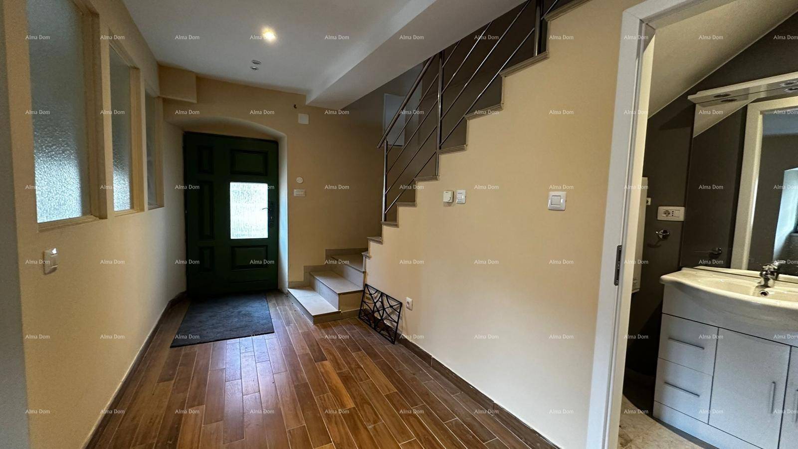 Eingangsbereich mit Holzfliesenboden, Treppe und Zugang zu einem Badezimmer.