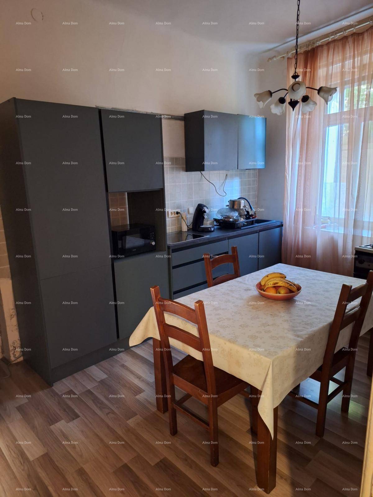 Küche mit grauen Schränken, Esstisch und Stühlen sowie einem Fenster mit Vorhängen.