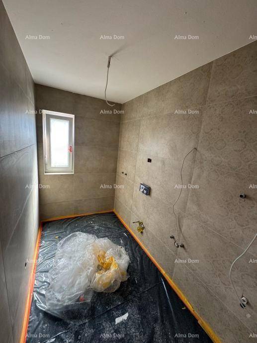Unfertiges Badezimmer mit grauen Fliesen an den Wänden und einem kleinen Fenster für Belüftung.