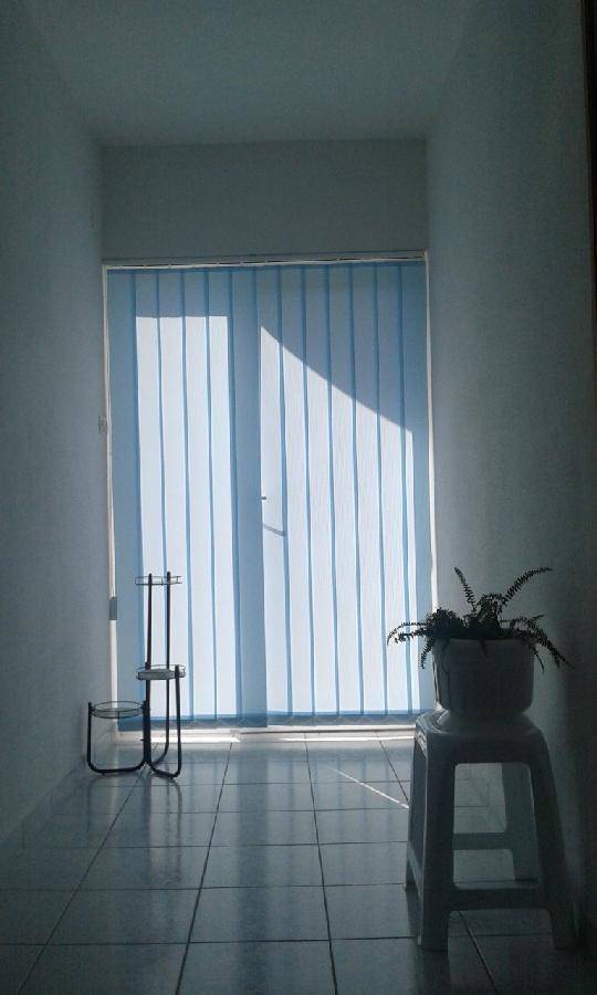 Heller Flur mit vertikalen Jalousien vor dem Fenster und einem gefliesten Boden, der viel Licht hereinlässt. 