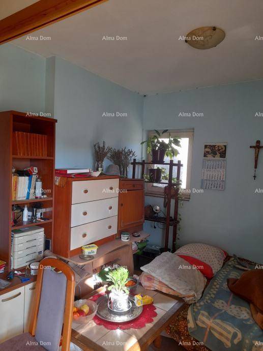 Schlafzimmer mit Bett, Bücherregal und Kommode, durch ein Fenster fällt Tageslicht herein.