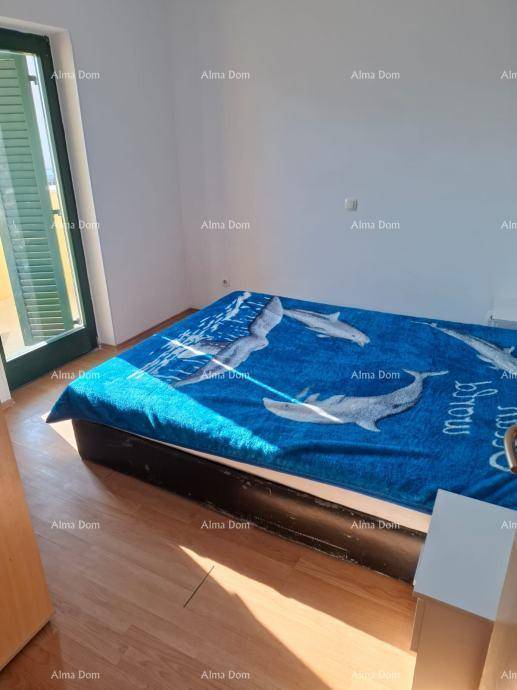 Schlafzimmer mit Bett und Zugang zu einem Balkon, ausgestattet mit Holzboden und Fensterläden.