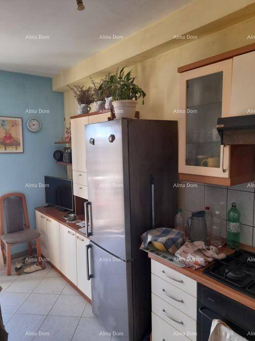 Küchenzeile mit Kühlschrank, Gasherd und Stauraum, daneben ein kleiner Fernseher.