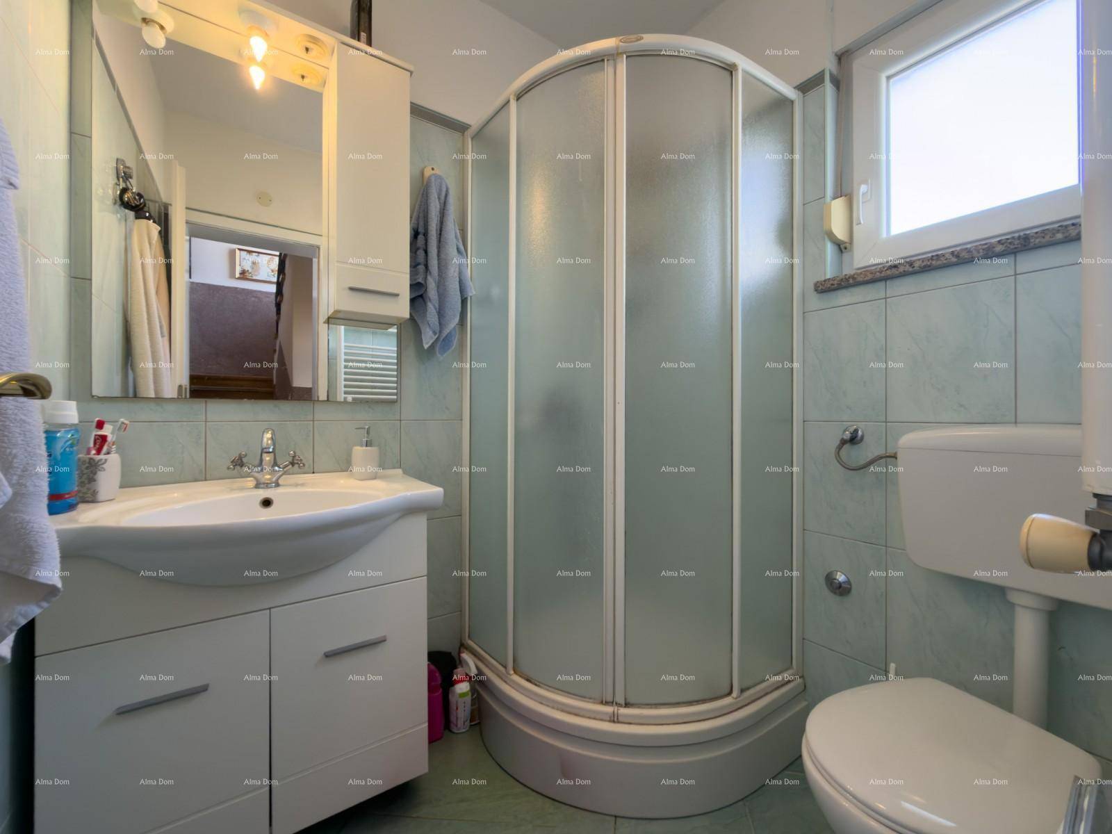 Badezimmer mit Duschkabine, Waschbeckenunterschrank und Fenster für Tageslicht.