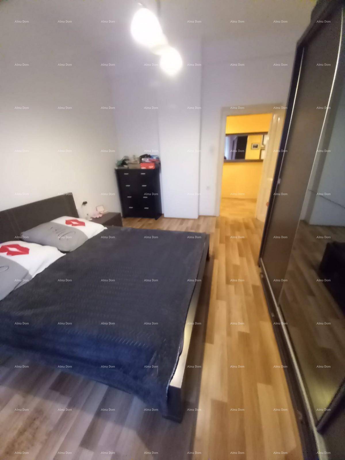 Schlafzimmer mit Doppelbett, großem Kleiderschrank und Holzboden, mit Blick in den Flur.