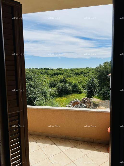 Weitläufiger Blick von einem Balkon über eine grüne, bewaldete Landschaft unter blauem Himmel.