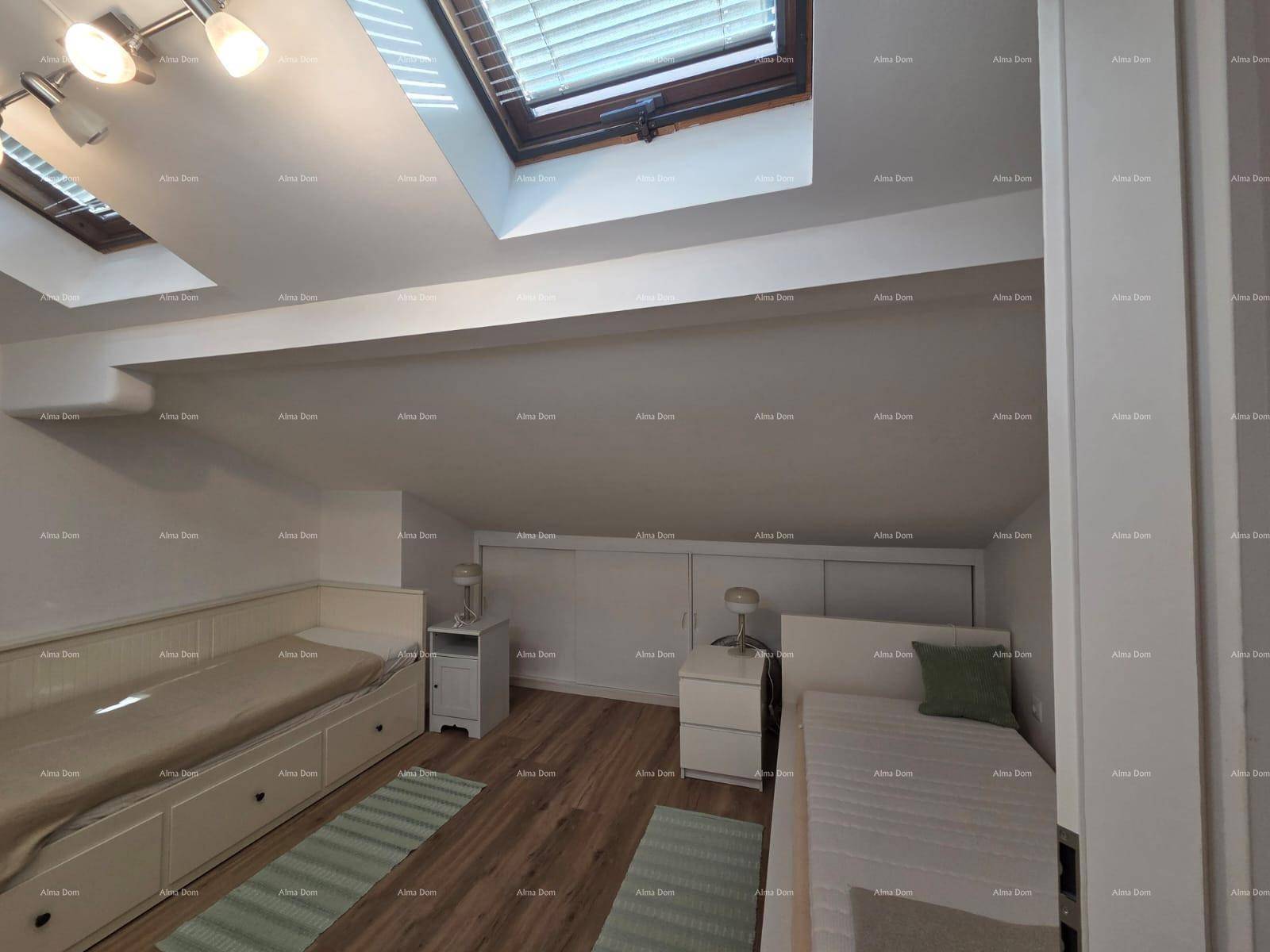 Dachgeschosszimmer mit zwei Einzelbetten, Dachfenstern und praktischen Stauraumlösungen.