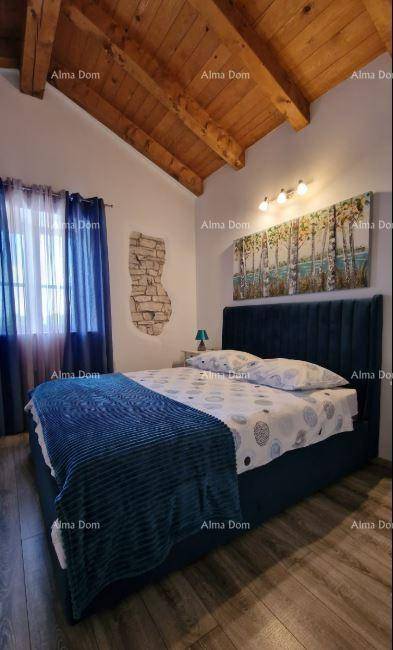 Gemütliches Schlafzimmer mit Doppelbett, Holzbalkendecke und blauen Vorhängen.