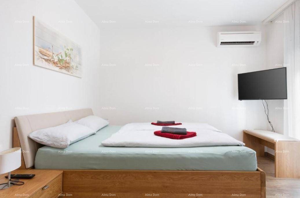 Helles Schlafzimmer mit hellem Holzdoppelbett, an der Wand montiertem Fernseher und Klimaanlage.