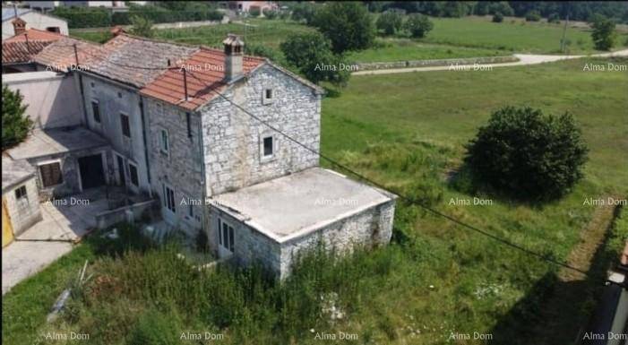 Altes Steinhaus mit Ziegeldach und umliegendem, verwildertem Grundstück in ländlicher Umgebung.