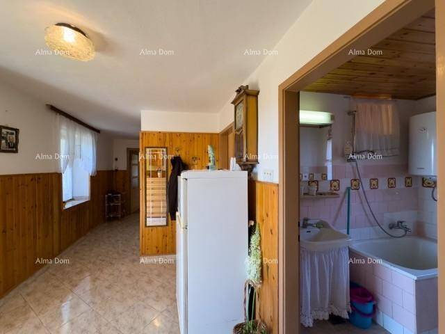 Flur mit Holzvertäfelung, Fliesenboden und Zugang zu einem Badezimmer, hell durch ein Fenster.