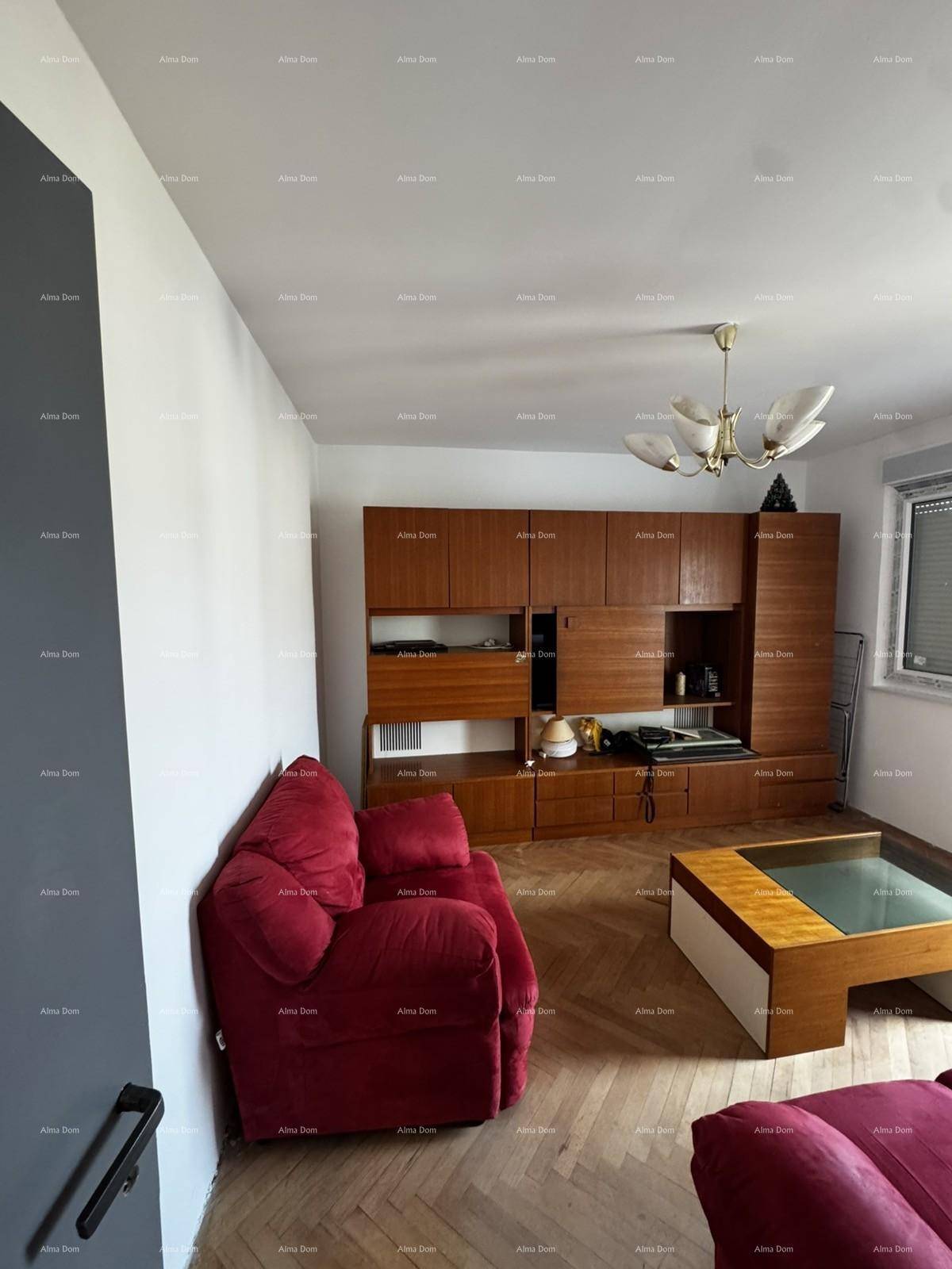 Wohnzimmer mit rotem Sofa, Holzschrankwand und Parkettboden, bereit für persönliche Gestaltung.
