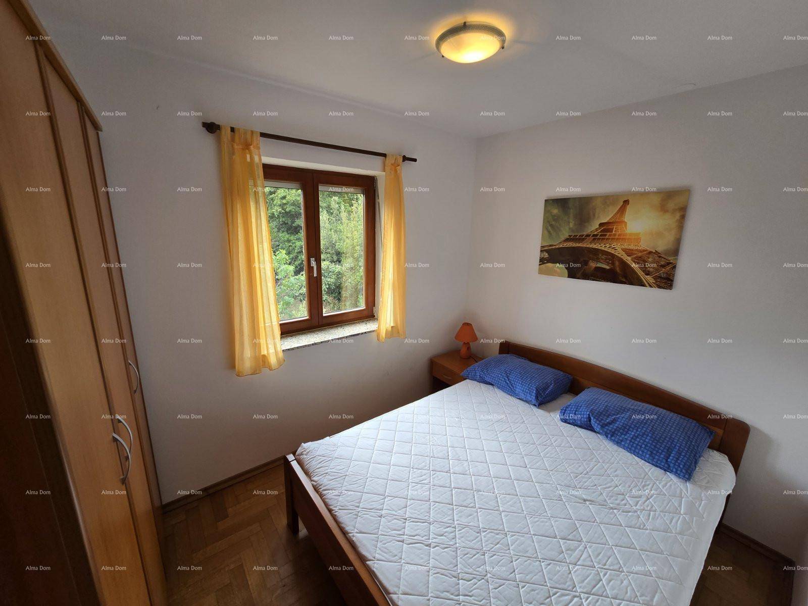 Schlafzimmer mit Doppelbett, Holzschrank und Fenster mit Blick auf die grüne Umgebung.