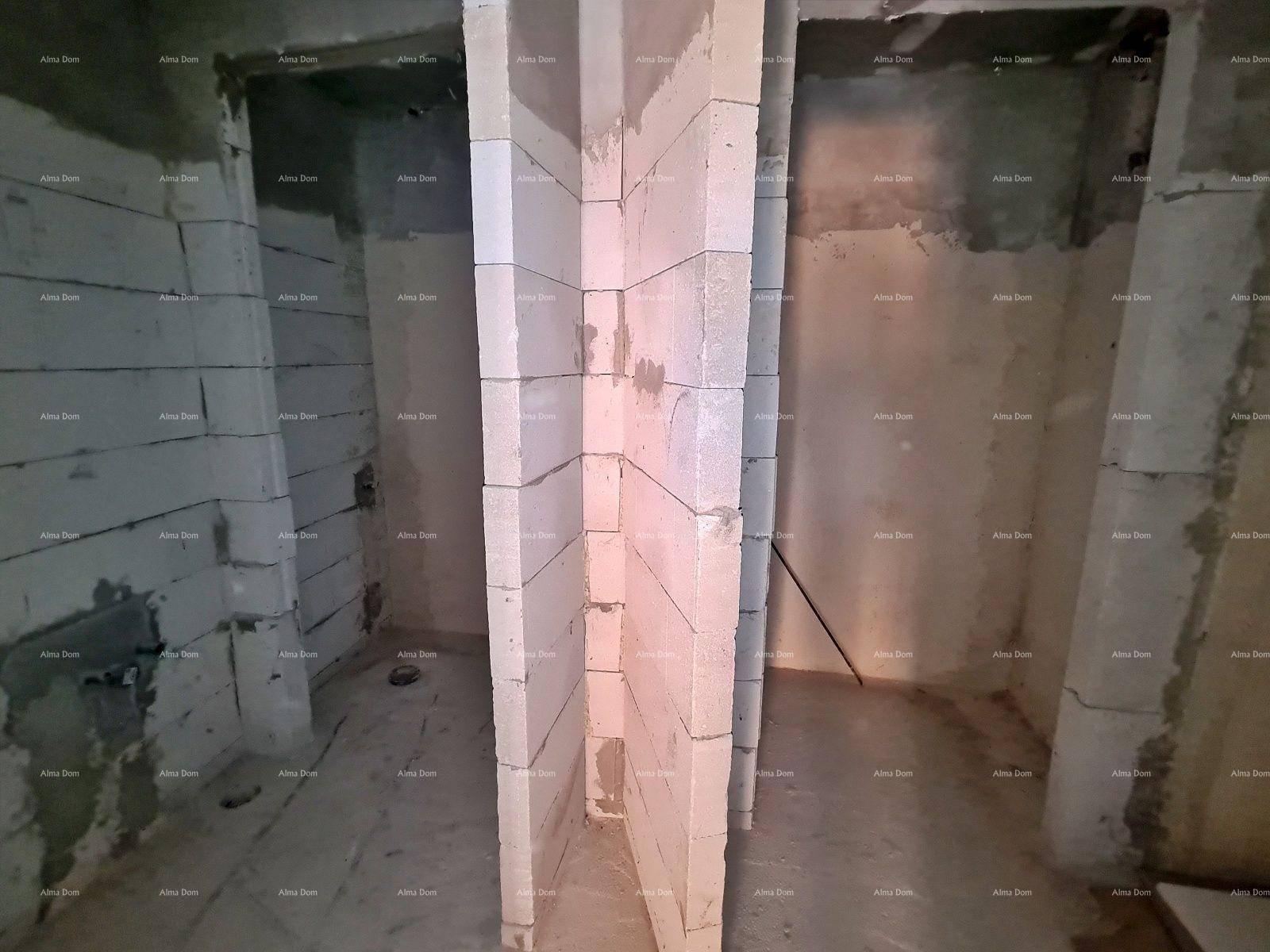 Innenraum im Rohbau mit unverputzten Wänden aus Betonsteinen und einem Durchgang.