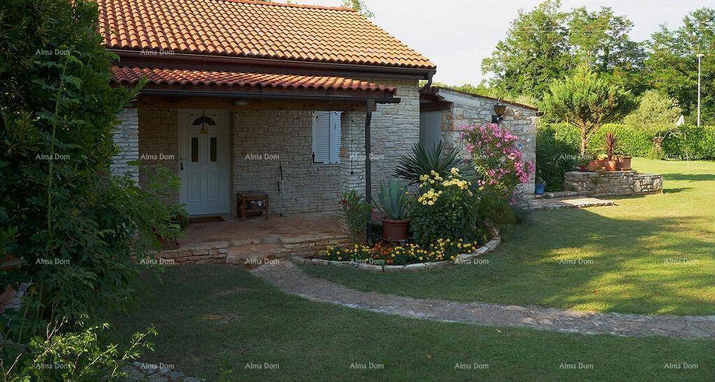 Traditionelles Steinhaus mit überdachtem Eingangsbereich, Blumenbeeten und einem gepflegten Gartenweg.