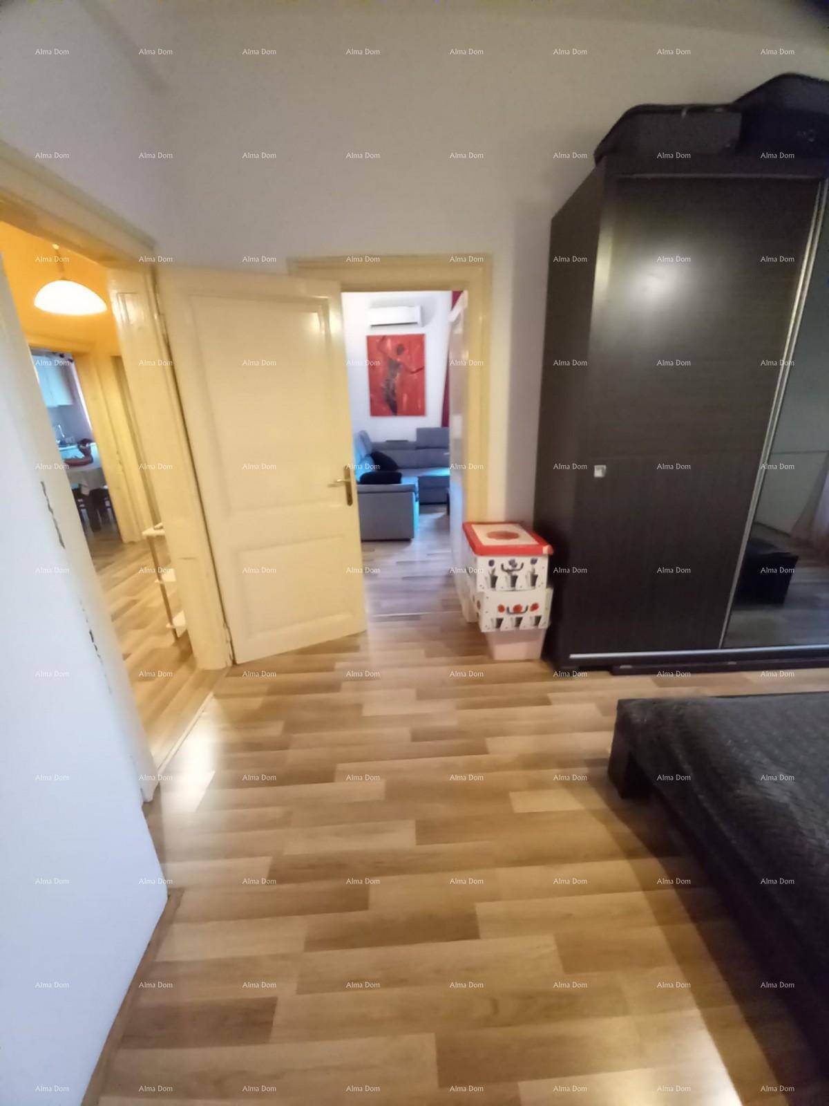 Schlafzimmer mit Holzboden und Zugang zu einem weiteren Raum, einfacher Einrichtung.