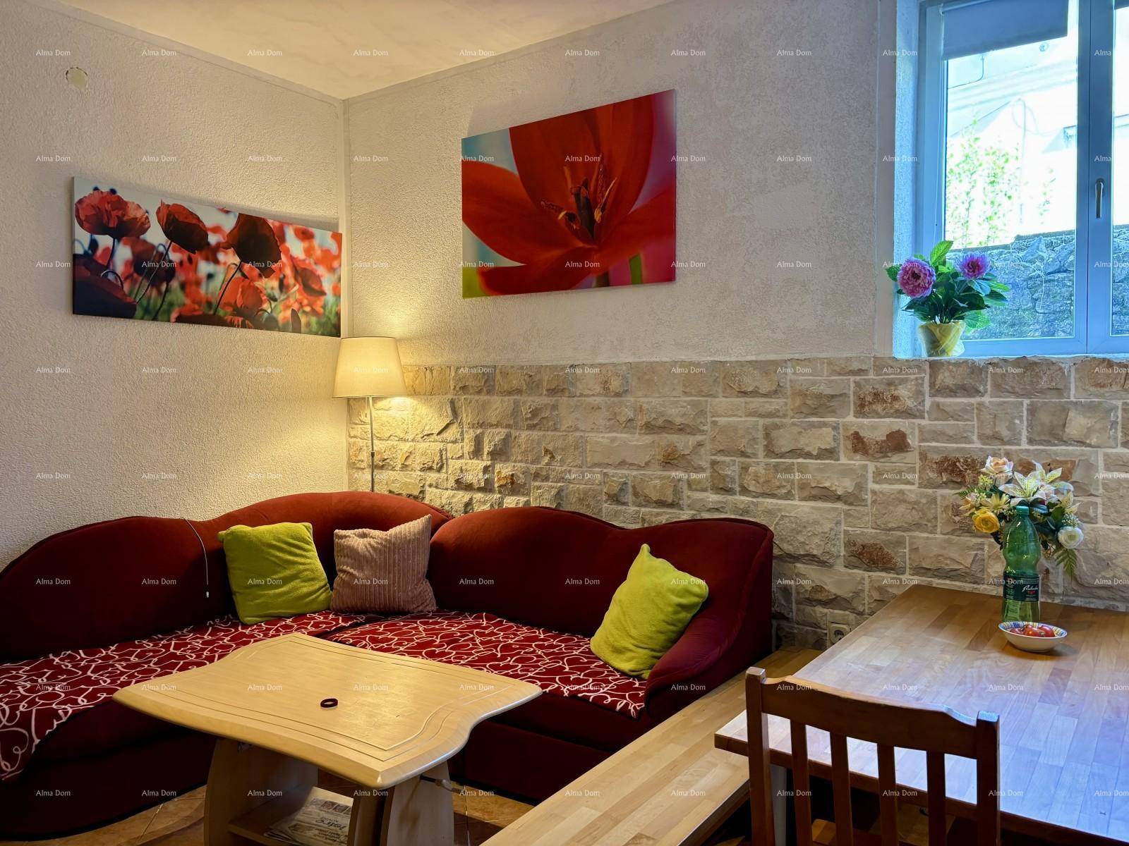 Detailansicht des Wohnbereichs mit bequemer Sitzecke, Holztisch und frischen Blumen am Fenster.