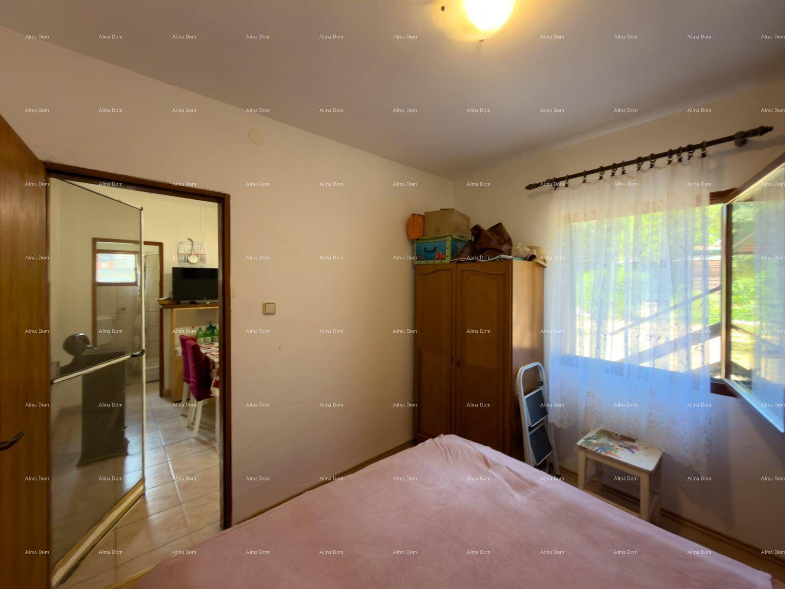 Gemütliches Schlafzimmer mit Bett und Kleiderschrank, durch die Tür ist die Wohnküche sichtbar.