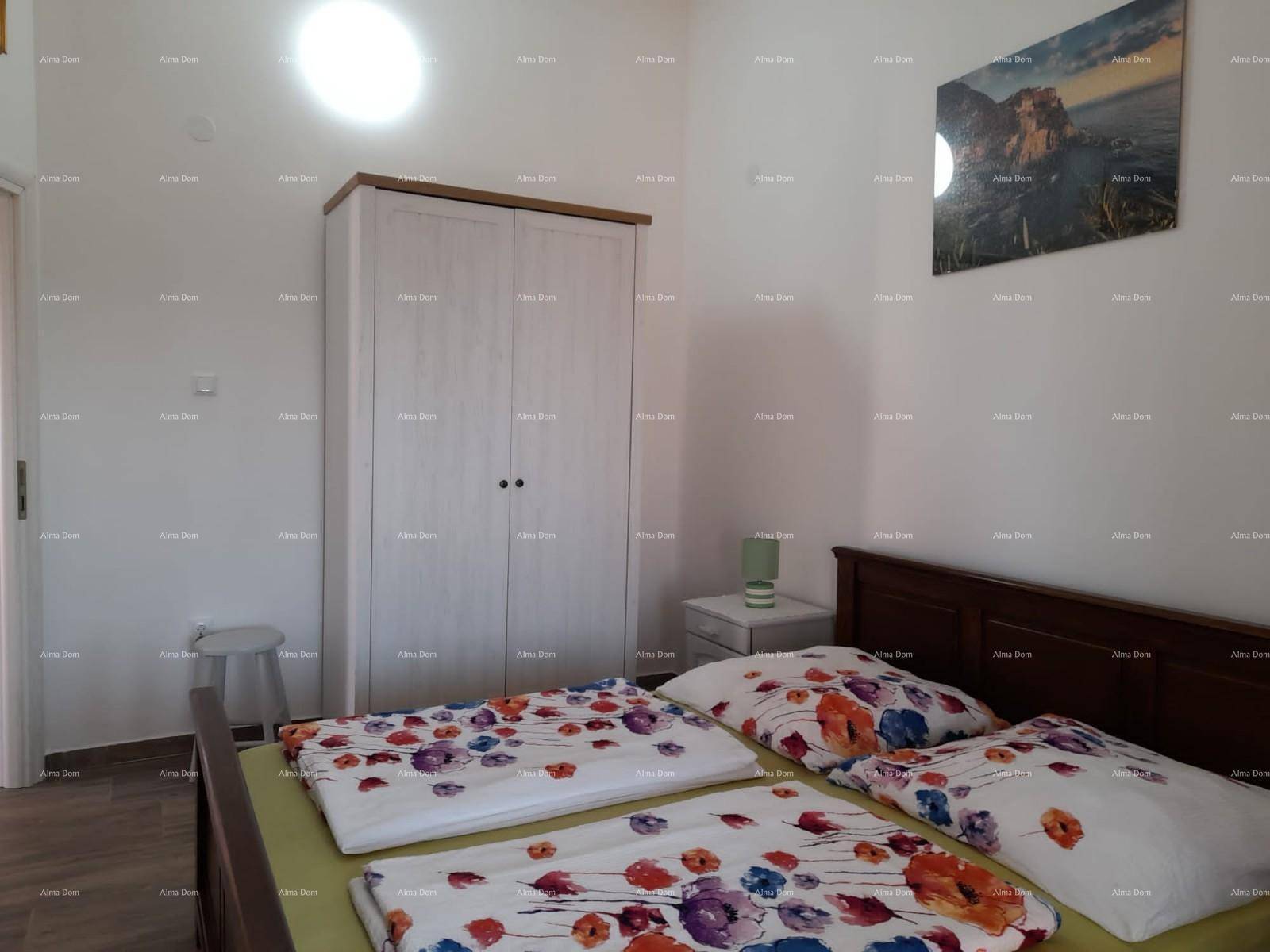 Helles Schlafzimmer mit Doppelbett, Kleiderschrank und floral gemusterter Bettwäsche.