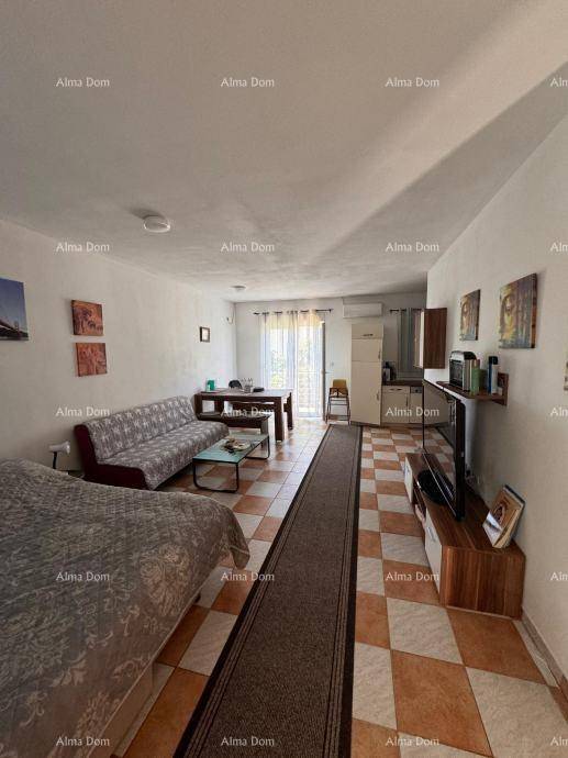 Kombinierter Wohn- und Essbereich mit Schlafbereich, gefliestem Boden und Zugang zum Balkon.