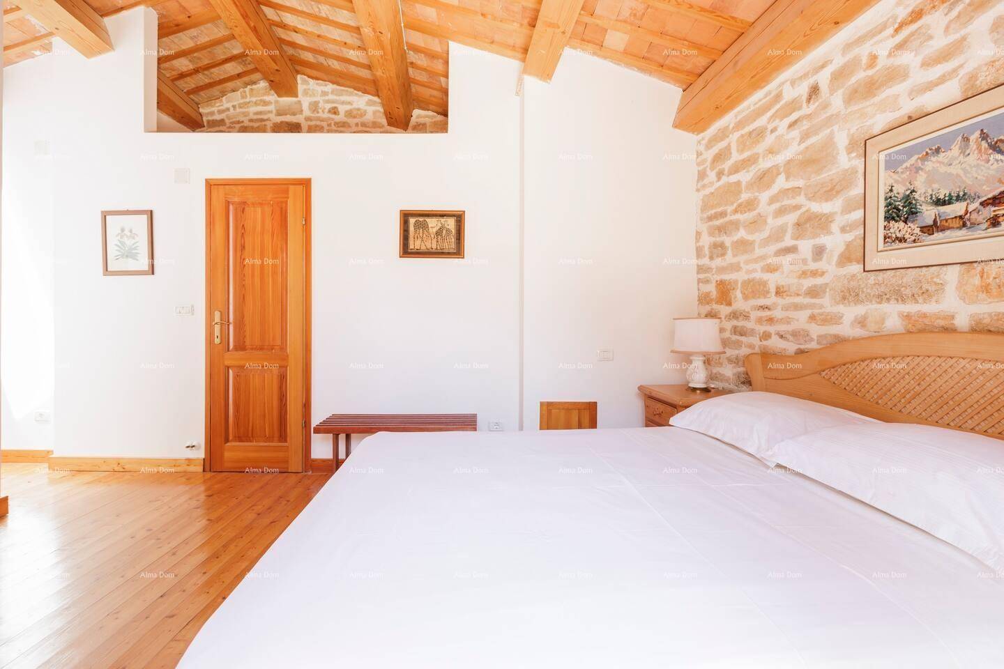 Helles Schlafzimmer mit Holzbalkendecke, freiliegender Steinwand und Holzboden.