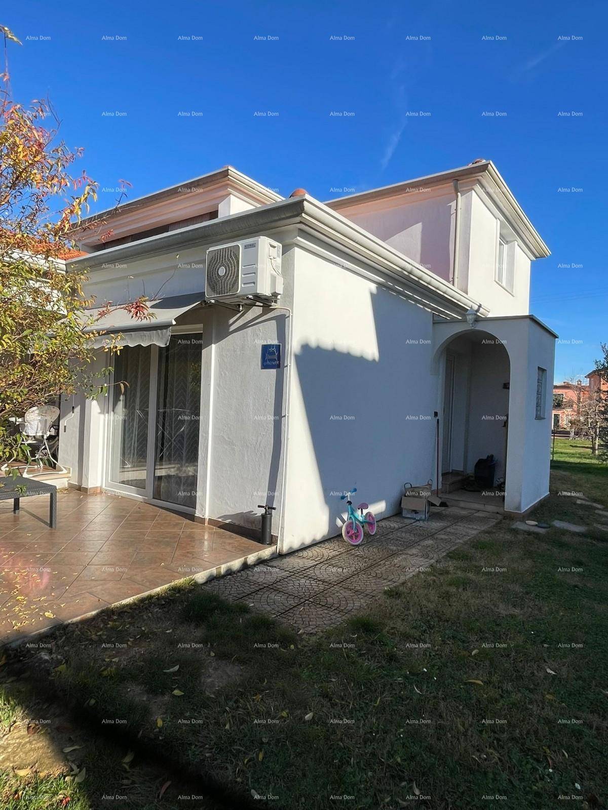 Geflieste Terrasse mit Zugang zum Garten, ausgestattet mit Gartenmöbeln und einer Klimaanlage an der Wand.