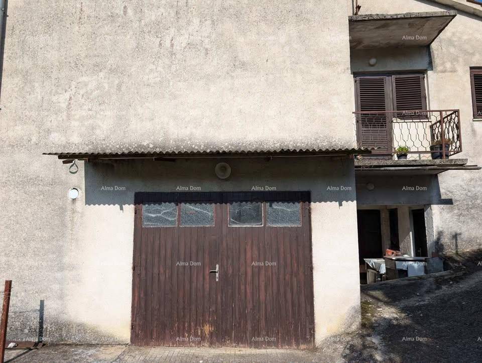 Fassade des Gebäudes mit einem großen hölzernen Garagentor und einem Wellblechdach.