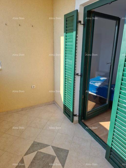Kleiner Balkon mit Fliesenboden und grünen Fensterläden, der Zugang zu einem Schlafzimmer bietet.
