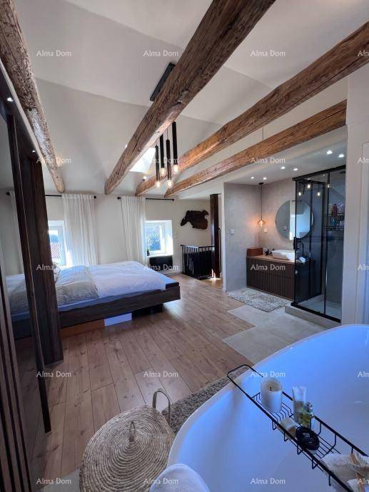 Helles Schlafzimmer mit Holzboden, freistehender Badewanne und offenem Duschbereich, unter sichtbaren Balken.