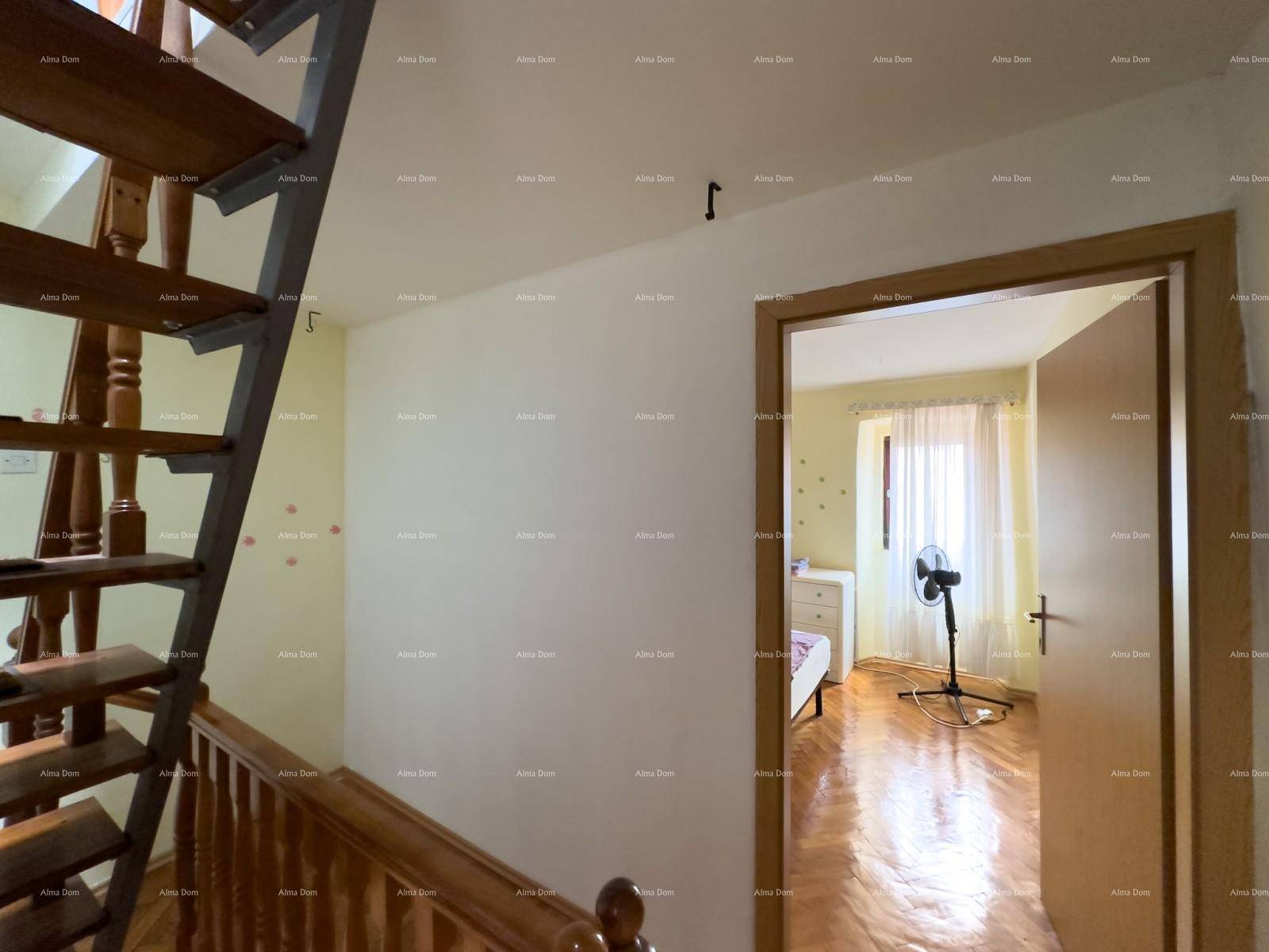 Blick vom Treppenabsatz in ein weiteres Schlafzimmer mit Holzfußboden und Fenster.