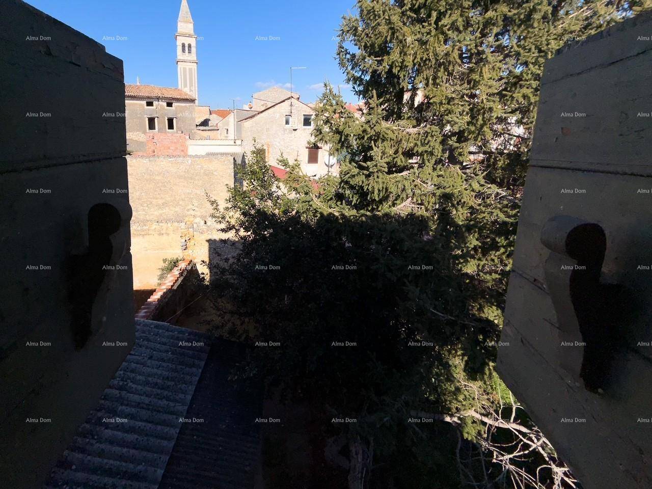 Blick aus dem Fenster auf die Dächer der Stadt und einen Kirchturm im Hintergrund unter blauem Himmel.