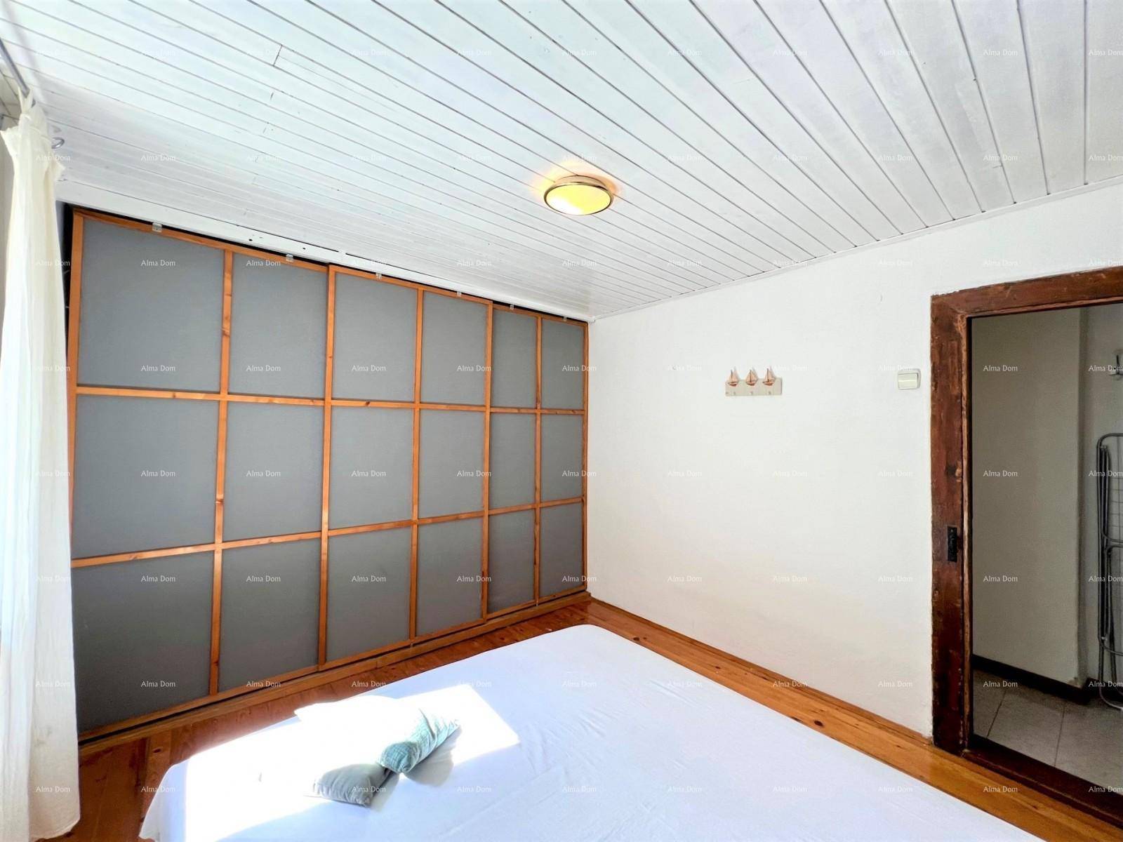 Schlafzimmer mit Holzdielenboden, weißer Holzdecke und einem großen Einbauschrank.