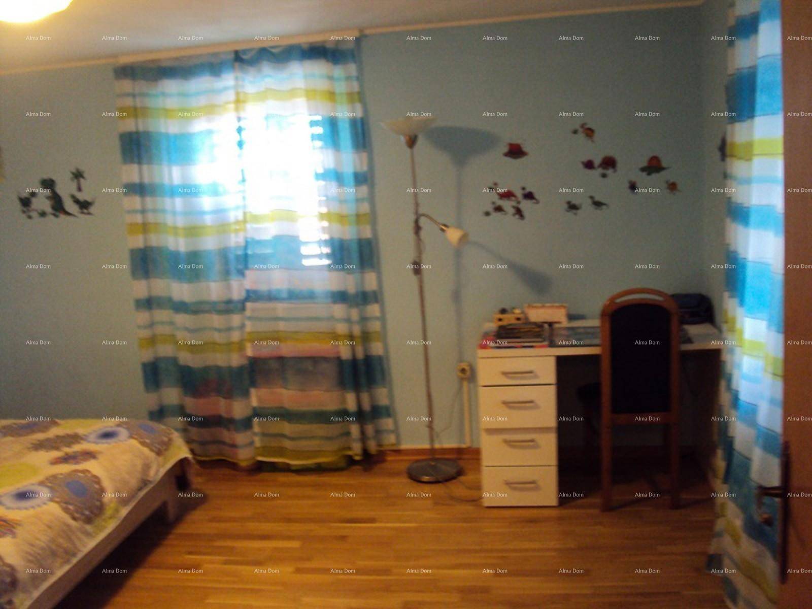 Kinderzimmer mit blauen Wänden, Holzboden, Schreibtisch und bunten Vorhängen.