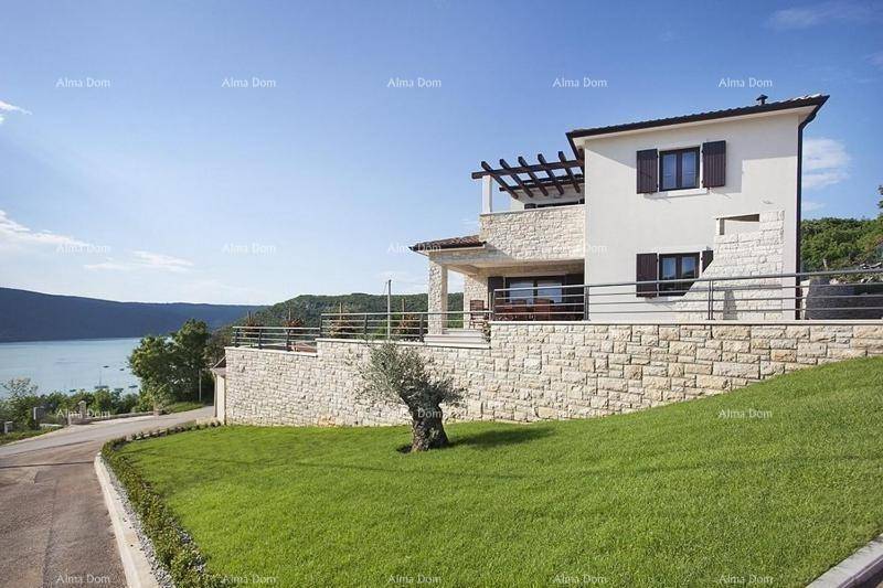 Elegantes Haus mit Steinfassade und Seeblick, eingebettet in eine gepflegte Grünanlage.