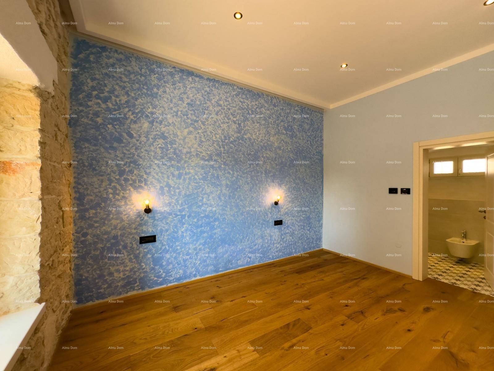 Schlafzimmer mit blauer Akzentwand, Holzboden und direktem Zugang zu einem Badezimmer.
