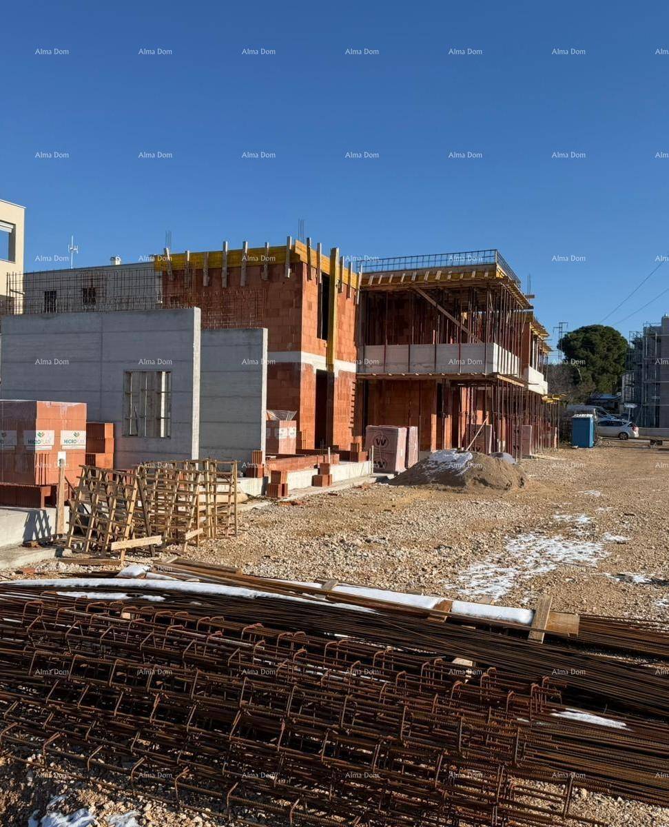 Baustelle eines Wohngebäudes mit Baumaterialien und Bewehrungsstahl im Vordergrund.