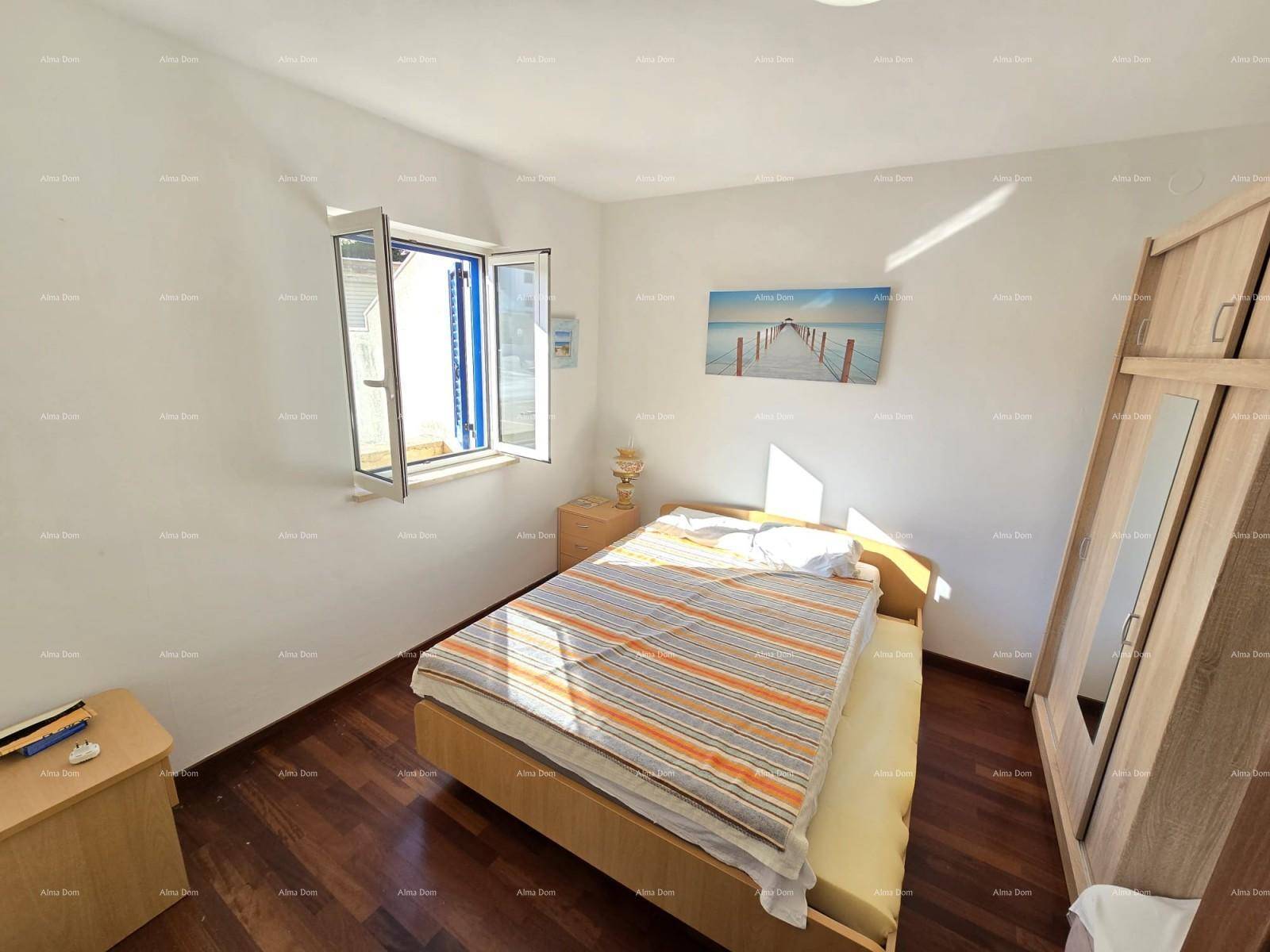 Schlafzimmer mit Doppelbett, Holzschrank und offenem Fenster mit blauen Fensterläden.