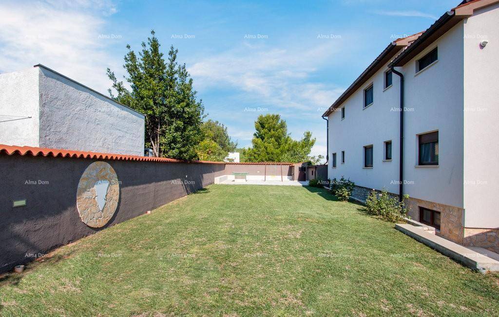 Gepflegter Rasenbereich neben dem Haus, umgeben von einer dekorativen Steinmauer.
