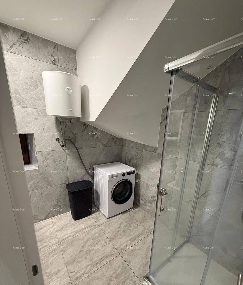 Badezimmer mit Waschmaschine, Duschkabine und schrägen Wänden unter dem Dach.