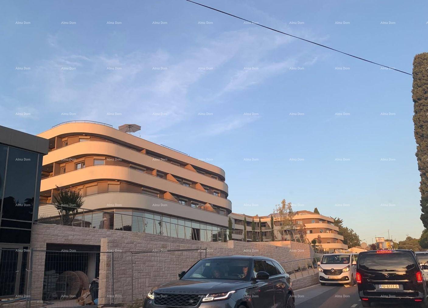 Geschwungenes modernes Gebäude mit mehreren Etagen, von der belebten Straße aus bei Tageslicht fotografiert.