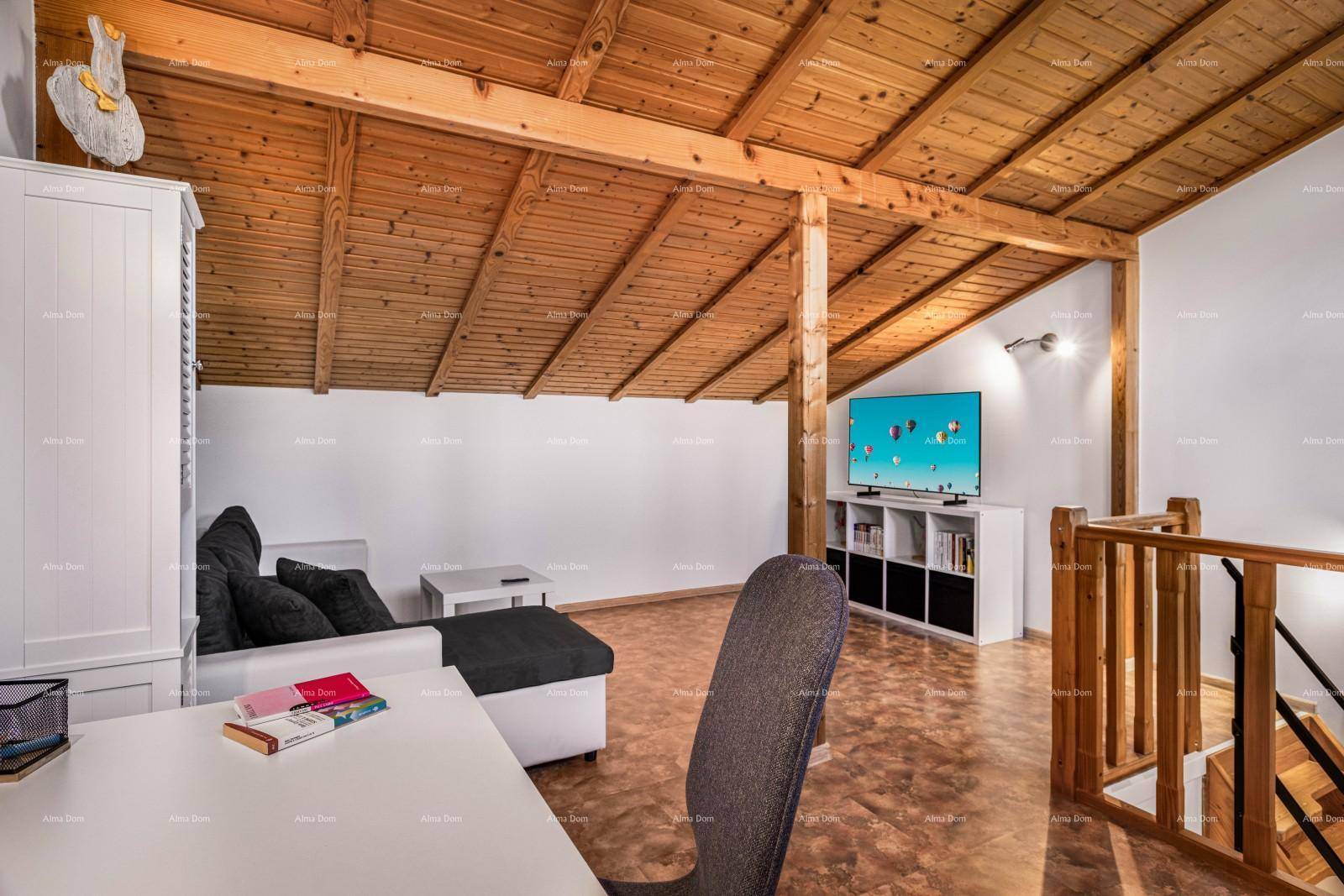 Gemütlicher Dachbodenbereich mit Holzbalken, Sofa und Fernseher, ideal als zusätzlicher Wohnraum.