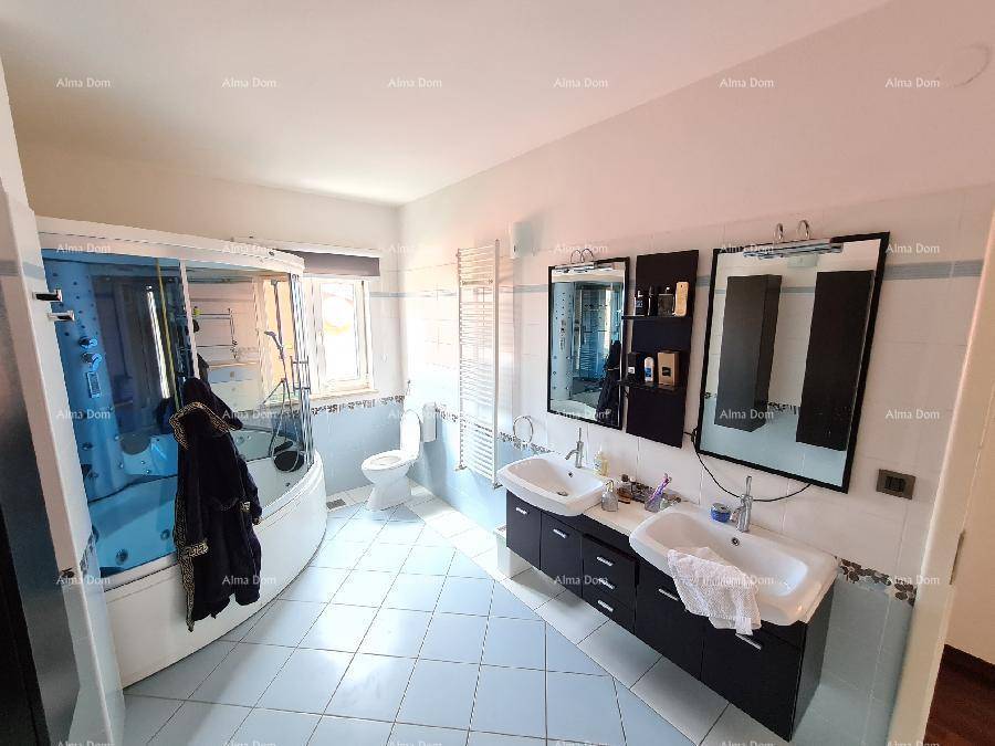 Geräumiges Badezimmer mit großer Badewanne, Doppelwaschbecken und hellblauen Fliesen.
