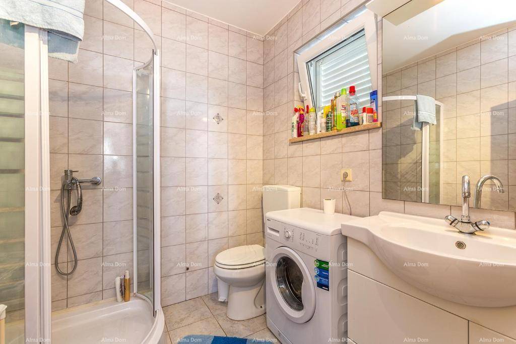 Praktisches Badezimmer mit Duschkabine, Waschbecken, Toilette und integrierter Waschmaschine.