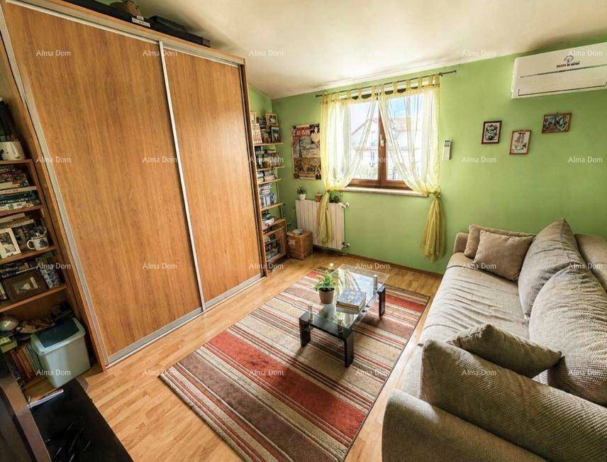 Helles Zimmer mit Schiebetürenschrank, Sofa, Holzboden und Klimaanlage.
