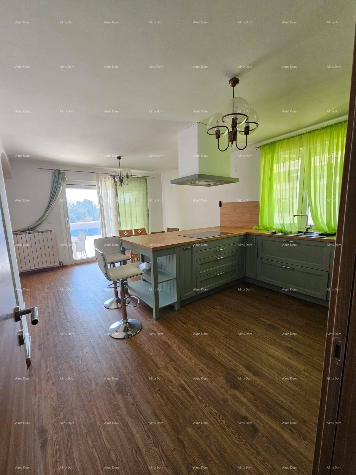 Helle Küche mit grünen Schränken, Holzboden und Zugang zu einem Balkon.