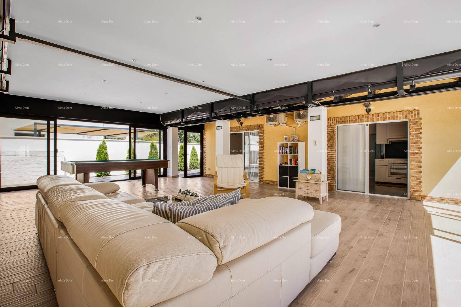 Geräumiger Wohnbereich mit Billardtisch, beigem Sofa und großen Fenstern zum Garten.