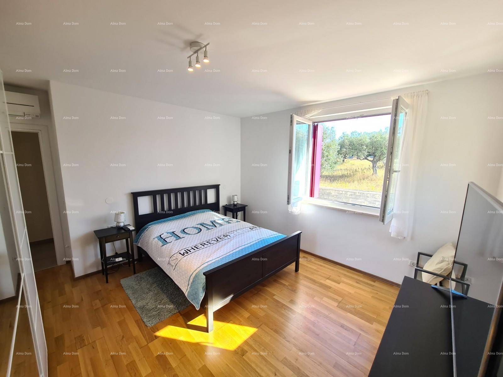 Helles Schlafzimmer mit Doppelbett, Holzparkett und Blick ins Grüne durch das Fenster.
